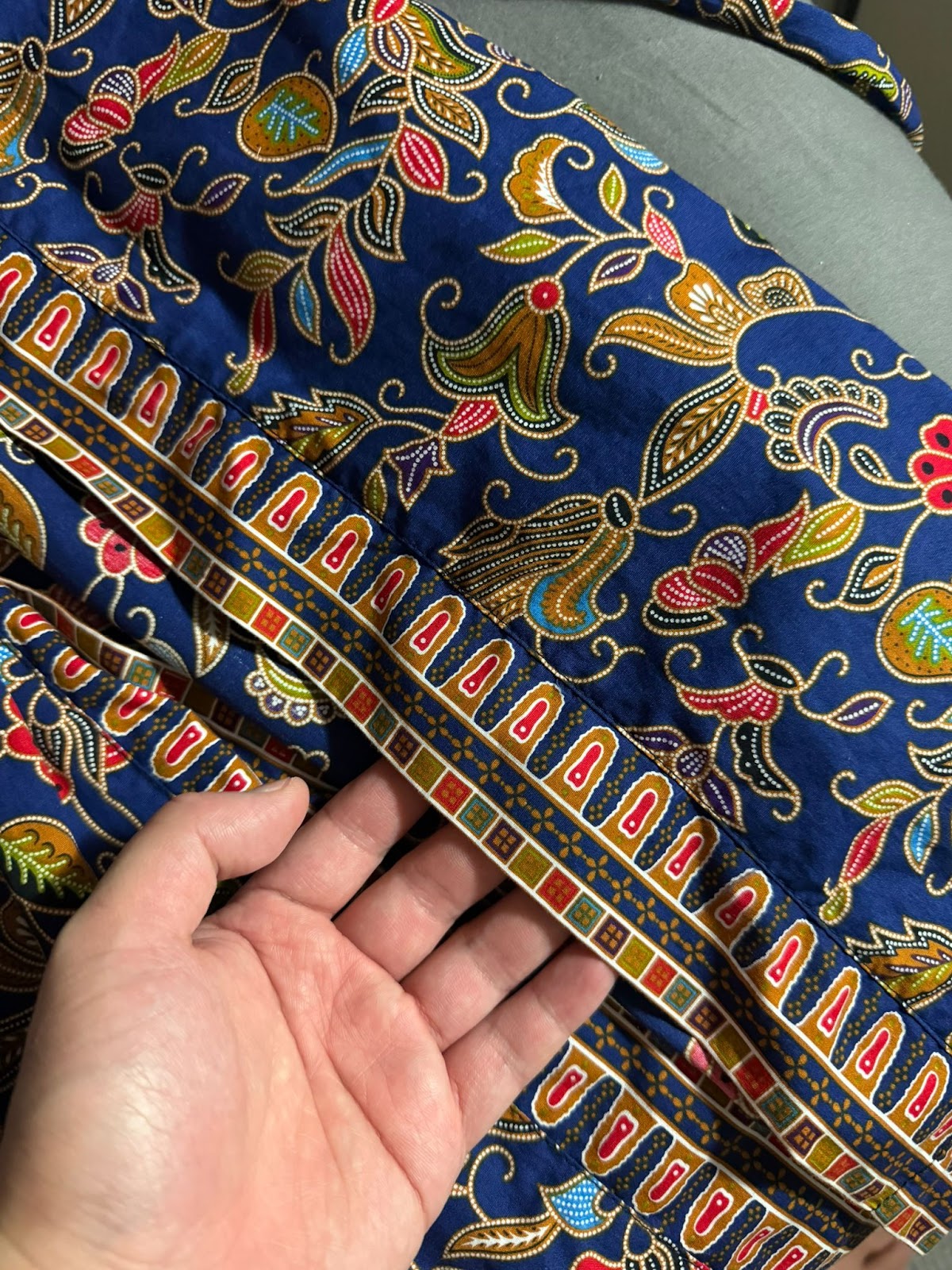 Close-up of a navy batik shirt with gold and red floral motifs